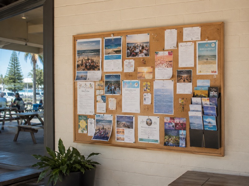 An outdoor community noticeboard covered with local flyers and posters